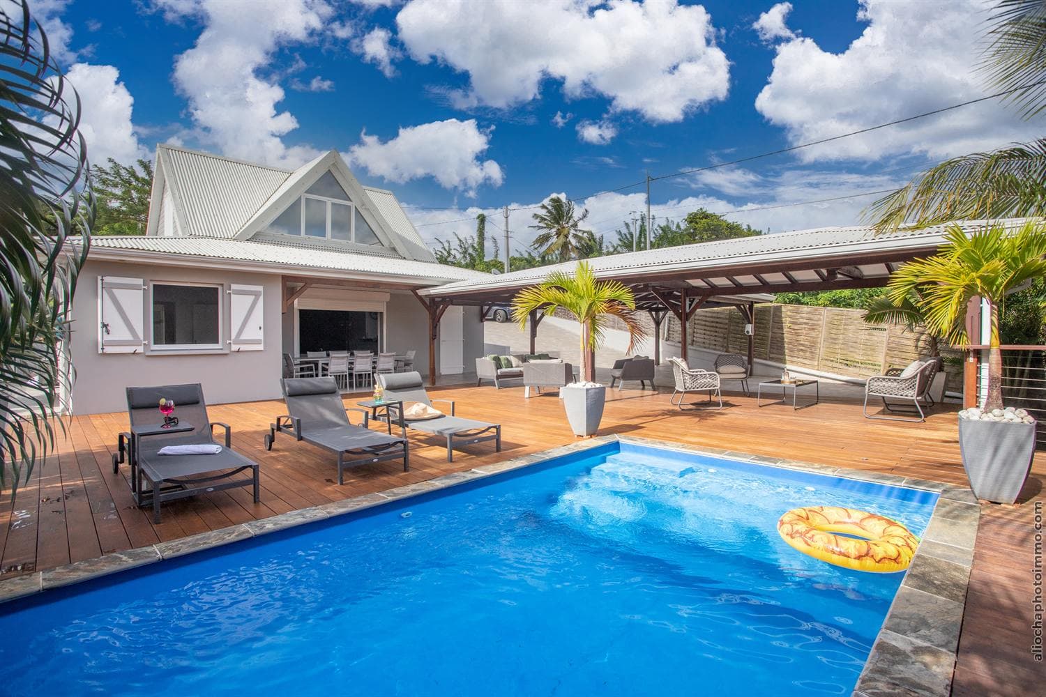 La villa, sa piscine et le grand deck en bois d'IPÉ bordé de palmiers